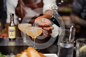 Barman hand decorating a cocktail glass filled with alcoholic drink