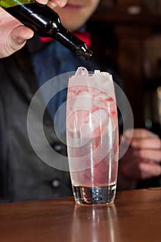 barman hands pouring red grenadine syrup into glass with alcohol cocktail and ice cubes