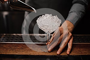 Barman holding a cocktail glass filled with ice