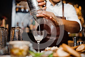 Barman i mixes a white cocktail using bar equipment