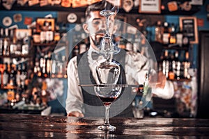Barman mixes a cocktail behind the bar