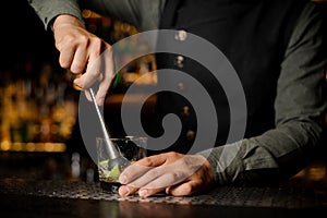 Barman mixing a cane sugar with lime in the glass