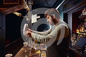 Barman mixing cocktail in shaker working in nightclub bar photo