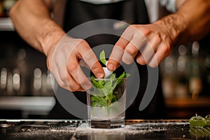 barman muddling sugar and mint in a glass