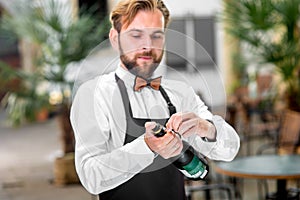 Barman opening bottle with sparkling wine