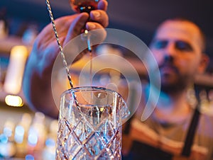 Barman pouring alcohol into empty glass to make drink in pub