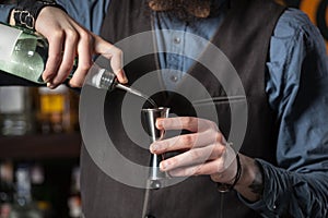 Barman pouring alcohol in the jigger.