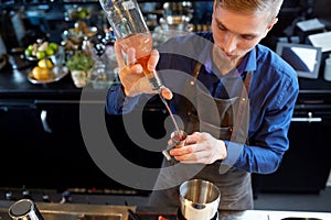 Barman pouring alcohol to cocktail jigger at bar