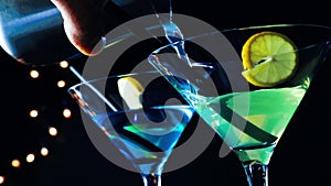 Barman pouring blue and yellow cocktail drink on a disco bar table, disco atmosphere