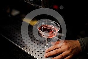 Barman pouring campari liquor into the cocktail