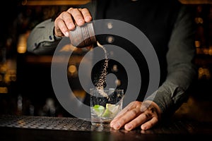 Barman pouring cane sugar into the cocktail glass
