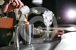 Barman pouring espresso into shaker at counter, closeup