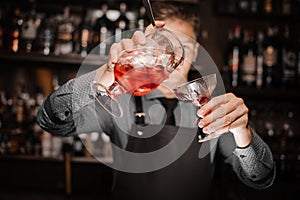 Barman pouring a fresh alcoholic cocktail into the cocktail glass