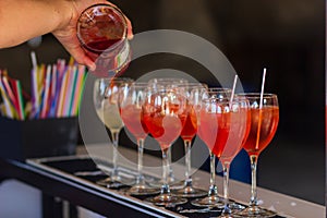 Barman pouring a fresh pink alcoholic cocktail into the elegant glass on the bar counter