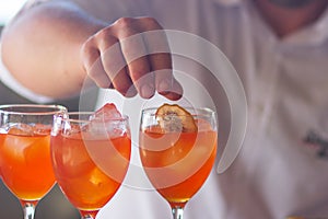 Barman pouring a fresh pink alcoholic cocktail into the elegant glass on the bar counter