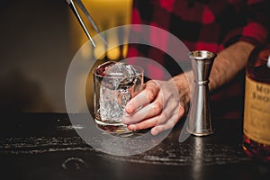 Barman pouring ice in glass.Bartender preparing cocktail drink.