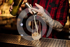 Barman pouring a portion of alcoholic drink using jigger