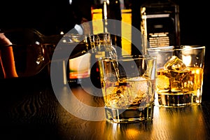 Barman pouring whiskey in front of bottles, focus on top of bottle