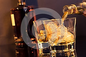 Barman pouring whiskey in front of whiskey glass and bottle