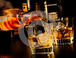 Barman pouring whiskey in front of whiskey glass and bottles