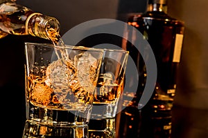 Barman pouring whiskey in front of whiskey glass and bottles photo