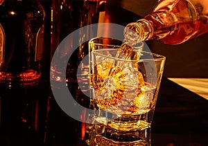 Barman pouring whiskey in front of whisky glass and bottles