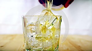 Barman pouring whiskey in the glass with ice cubes on wood table background, focus on ice cubes, whisky relax time, gold warm