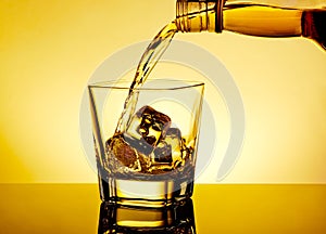 Barman pouring whiskey in the glass on table with reflection, warm tint atmosphere