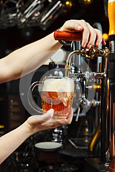 Barman pours beer into a glass goblet from the tap