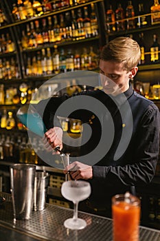 Barman pours blue syrup for cocktails into jigger to measure