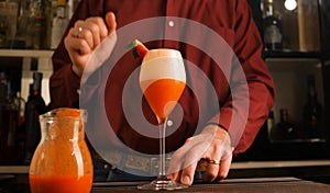 Barman prepares an Italian cocktail called Fragolino with strawberry juice and sparkling wine