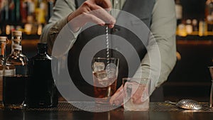 Barman preparing fresh cocktail cosmopolitan into traditional glass