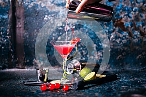 Barman preparing and pouring red cocktail in marini class. cosmopolitan cocktail on metal background