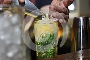 Barman puts ice in a cocktail