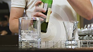 Barman puts ice into glass pours whiskey in cafe