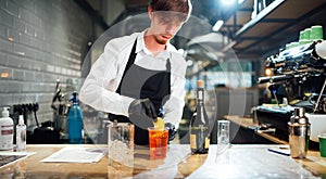 Barman puts a slice of orange on a glass with a cocktail. Drink preparation process.