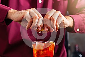 Barman squeezes the lemon peel into the cocktail photo