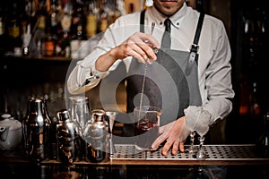 Barman stirring fresh summer alcoholic cocktail in glass