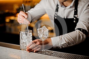 Barman stirring ice cubes in a glass