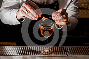 Barman in a white shirt making a cocktail with a smoky note