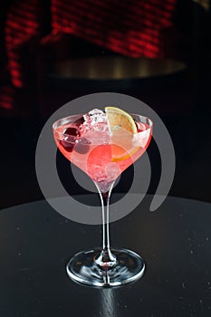 Barman at work, preparing cocktails. pouring cosmopolitan to cocktail glass.