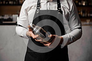 Barmans hands holding a shaker against the bar counter