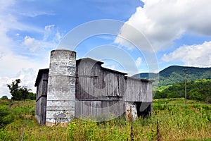 Barn Has Roofless Silo and Weathered Exterior photo