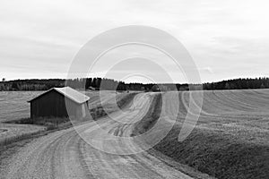 Barn on the roadside. Countryside road. Image in black and white.