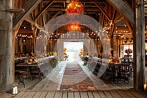 A barn transformed into a functional space with tables, chairs, and hanging lights suspended from the ceiling, Barn wedding in a