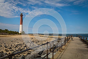 Barnegat Lighthouse on Long Beach Island, NJ, on a sunny spring day with blue sky dotted with clouds