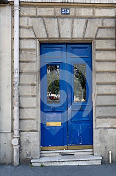Double door panels with door windows with reflective glass protected by ornate lattice. Blue painted antique door