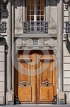 Beautiful antique double door entrance of old building in Paris France. Vintage wooden doorway and whimsical stucco fretwork wall