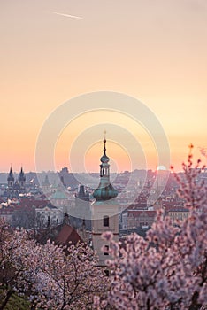 Baroque chapel bell tower steeple at historical part of city on the background of an orange red sunrise sky.