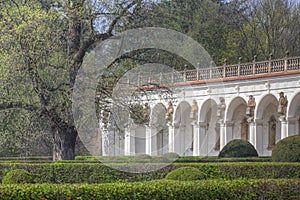 Baroque colonnade with statues and hedges